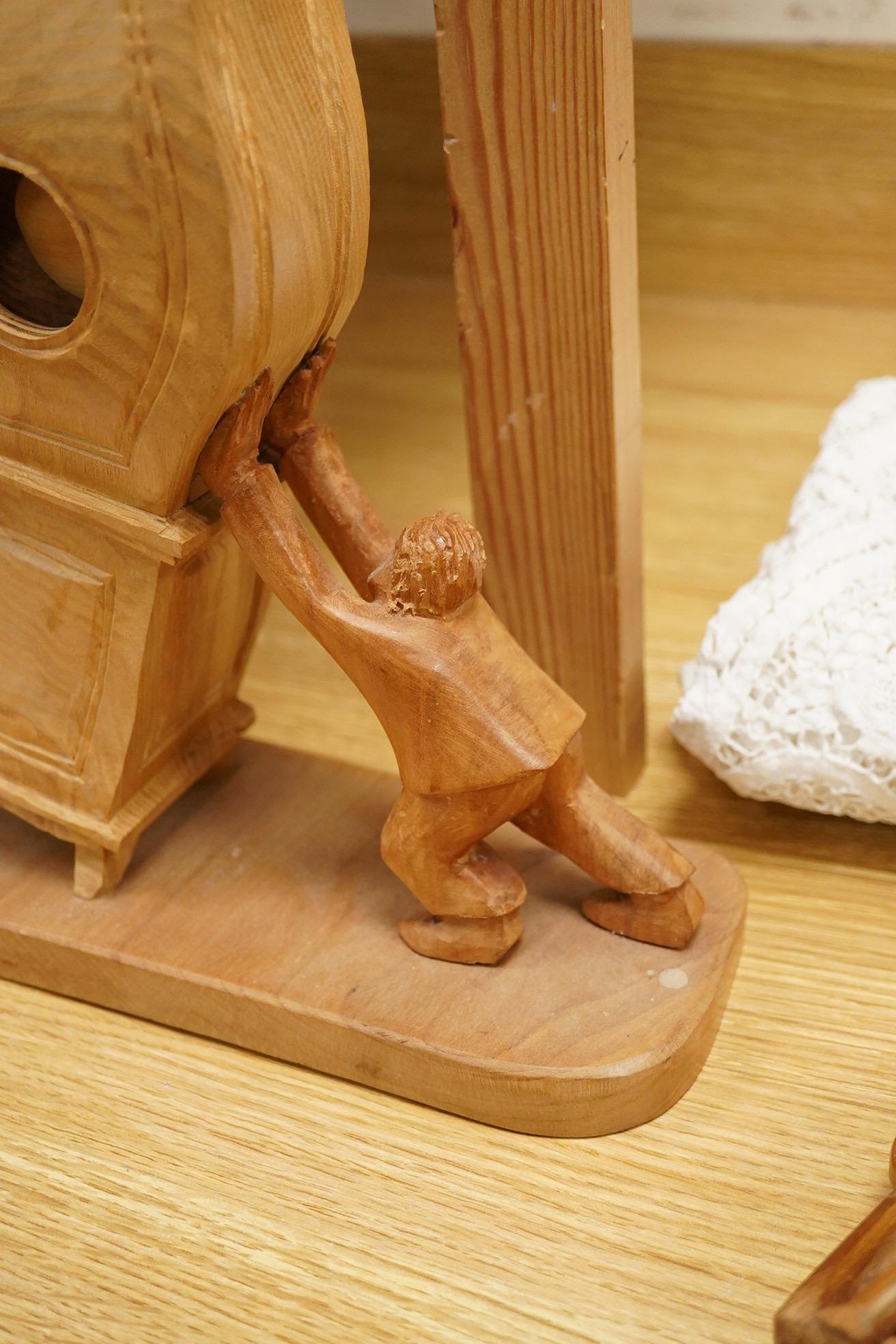 Pierre Decorse (b.1953), a naturalistically modelled wooden sculpture of a grandfather clock and a figure, together with two other sculptures comprising a suitcase and figure, largest 42cm high